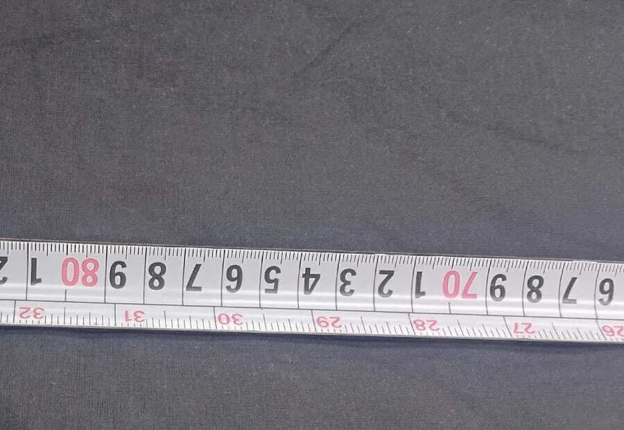 A close view of tape measure graduations resting on dark grey woven cotton.